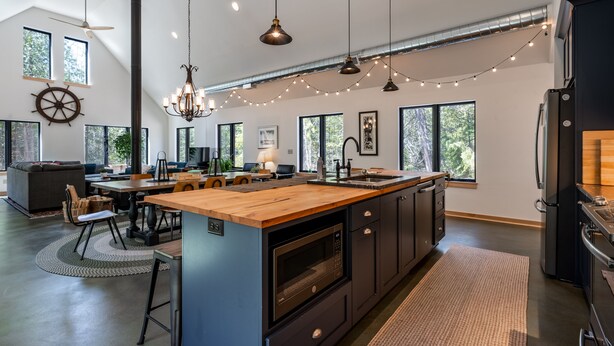A modern kitchen with a central island, pendant lighting, and large windows.