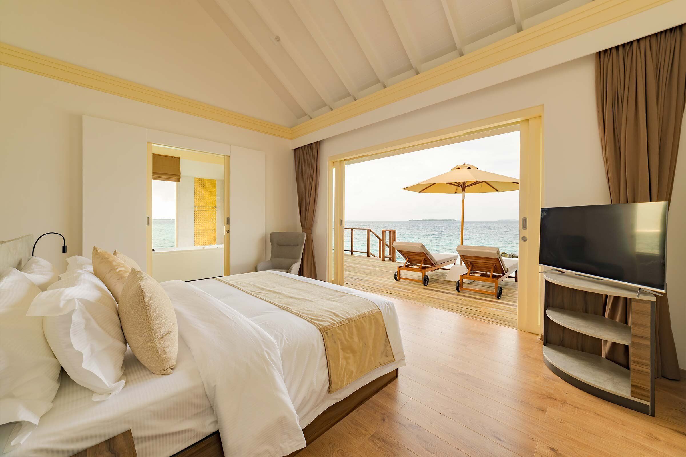 Una camera da letto con un letto, una televisione e vista sul mare.