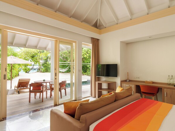 A modern hotel room with a large bed, a TV, a desk, and a view of the outdoors. - Siyam World Maldives - All-inclusive (Dhigurah)