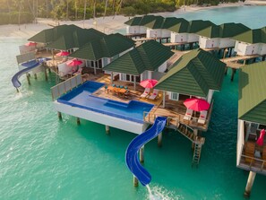 Overwater bungalows with a pool, slides, and beach access.
