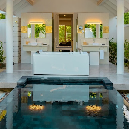A modern bathroom with two sinks, a large bathtub, and a small pool.
