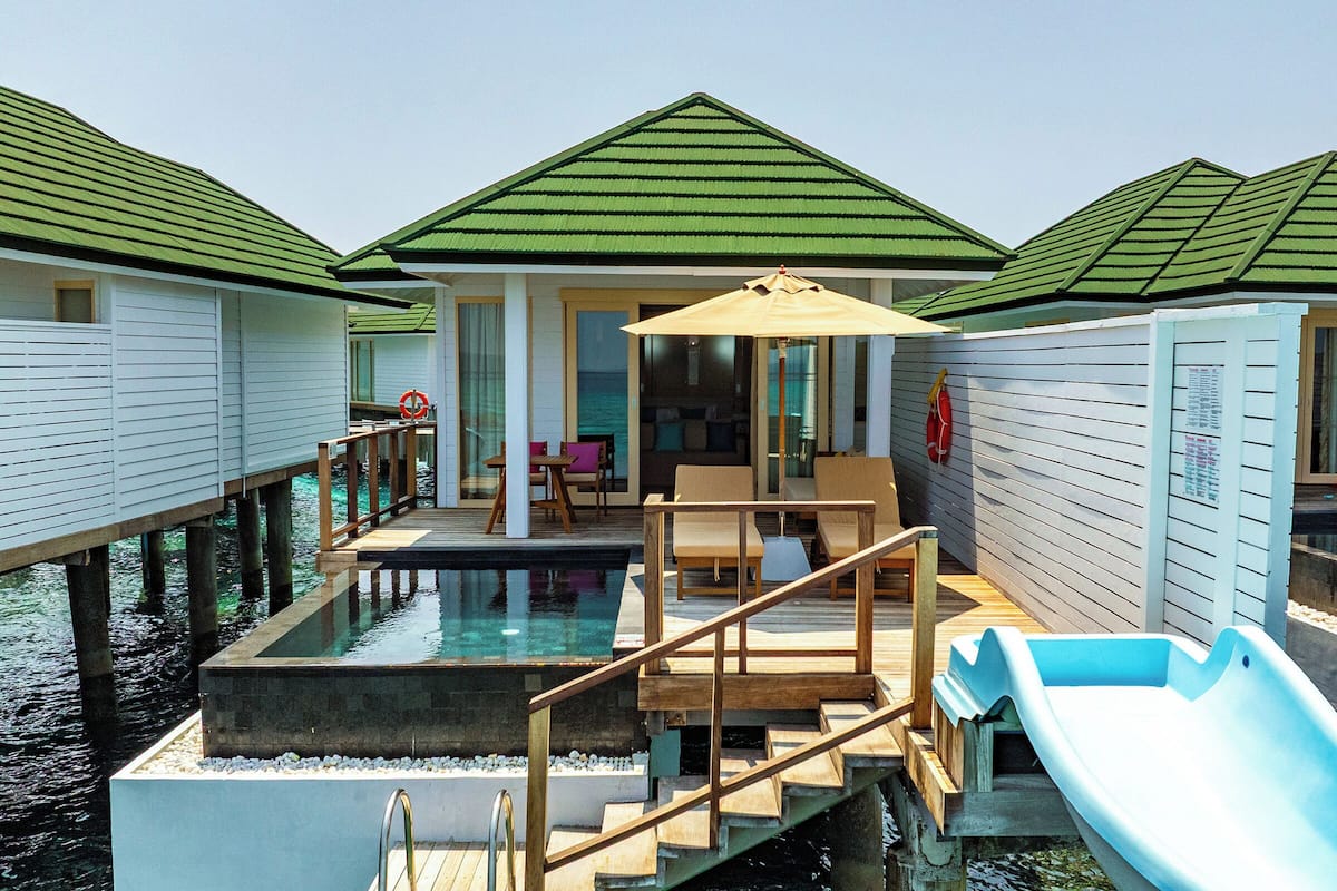 A resort with overwater bungalows, a pool, and a slide.
