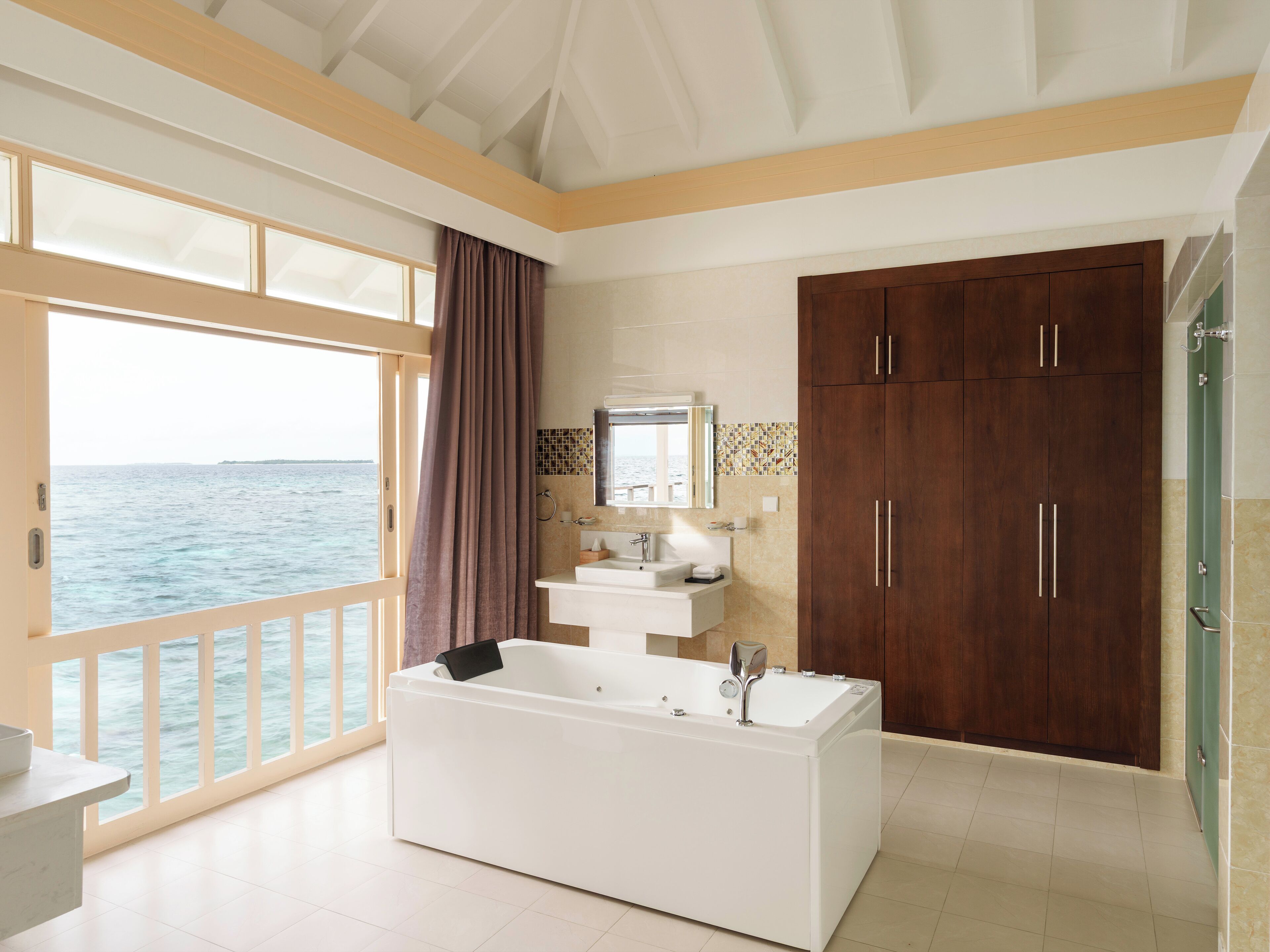 Une salle de bain moderne avec une grande baignoire, des meubles en bois et une vue sur la mer.
