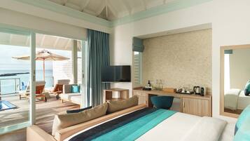 A hotel room with a large bed, a desk, a TV, and a balcony with a view of the sea.