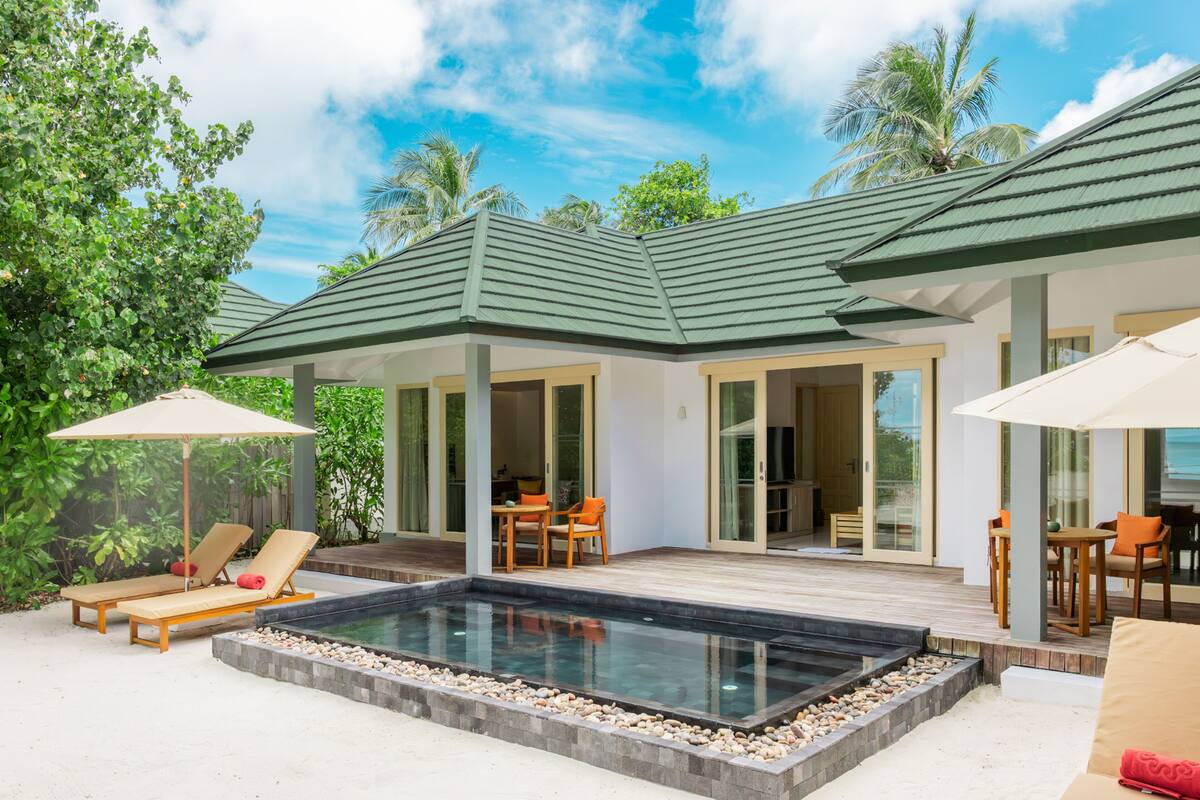 A modern villa with a swimming pool, outdoor seating, and a covered patio.