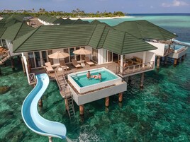 Una villa sobre el agua con piscina, zona de estar y un tobogán.