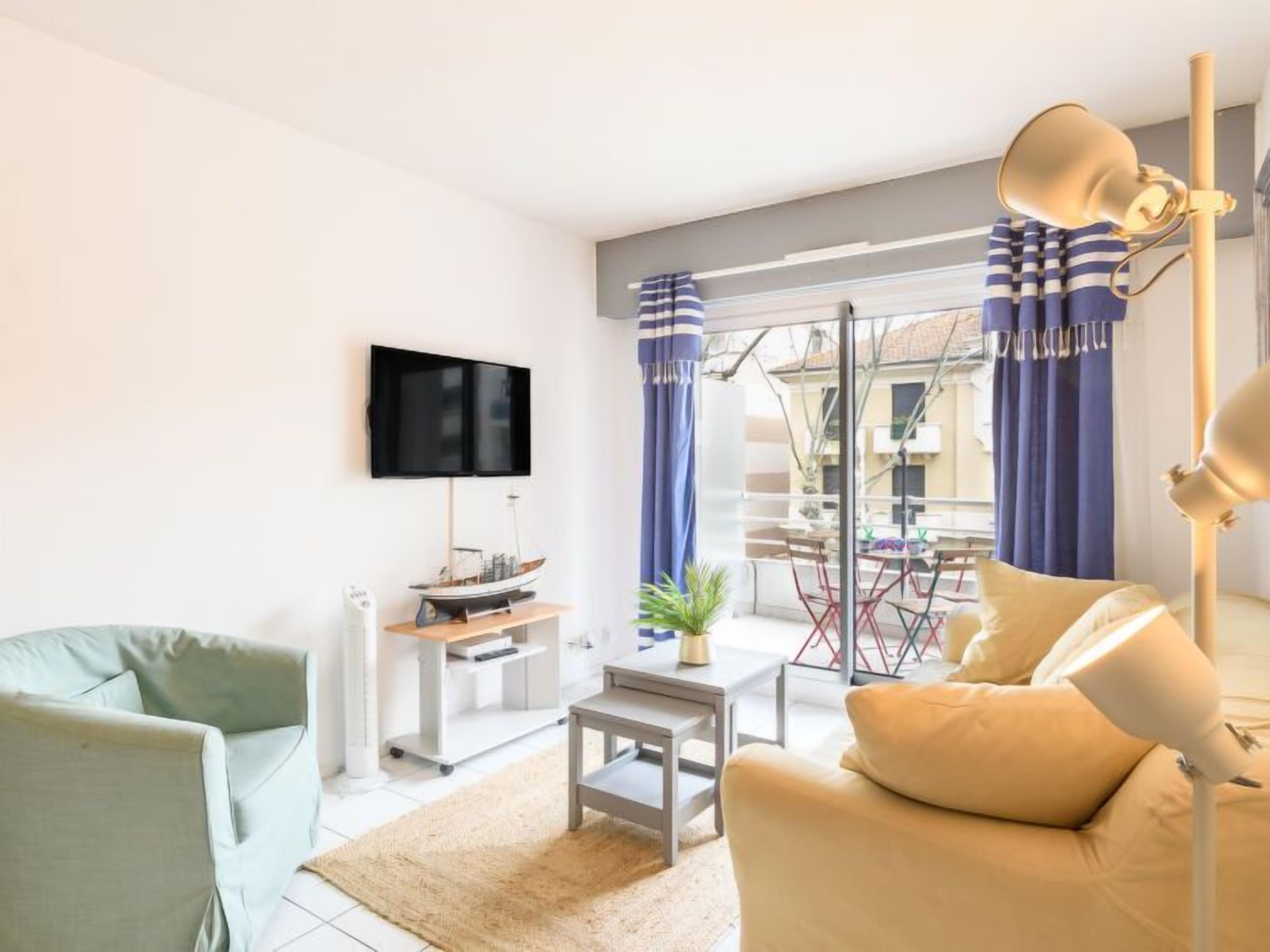 A modern living room with a flat-screen TV, a sofa, a coffee table, and a lamp.