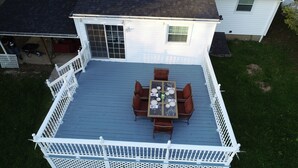 Une terrasse couverte, dotée d’une table et de chaises, et entourée d’une clôture blanche.