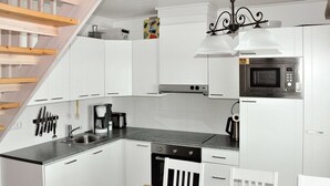 A modern kitchen with white cabinets, a black countertop, a microwave, a coffee maker, and a dining area with a table and chairs.