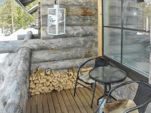 A wooden log cabin with a glass door, a lantern, and a stack of firewood. - Maahisenrinne 3 e 19 by Interhome (Äkäslompolo)