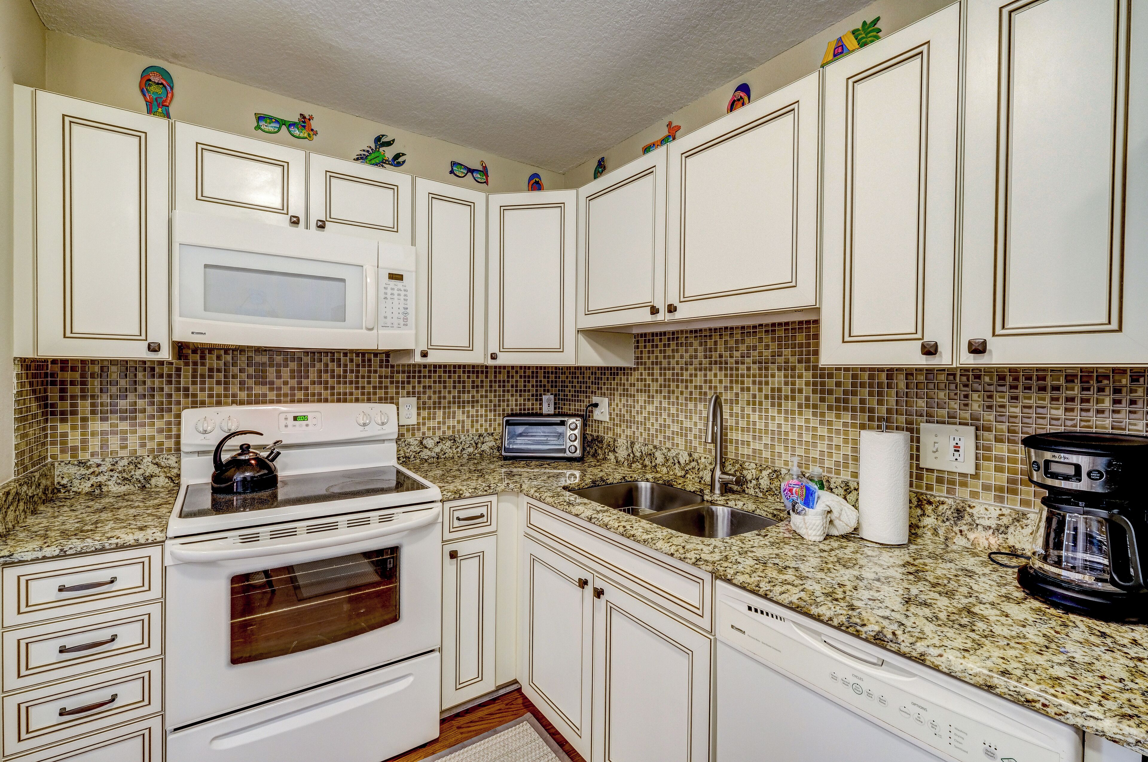 A kitchen with white cabinets, a microwave, stove, and a coffee maker.