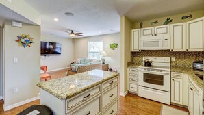 A compact kitchen with white cabinets, a microwave, an oven, and a granite countertop.