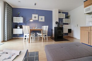 Un salon moderne comprenant un canapé, une table à manger avec des chaises, une cheminée et un coin cuisine avec des placards et un four à micro-ondes.