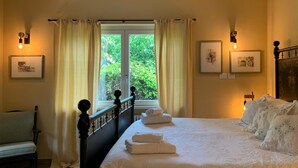 A bedroom with a large bed, a window with curtains, a chair, and wall-mounted lights. - Villa La Bolvedrina: private garden with BBQ, 100 meters from the Lake. (Tremezzina)