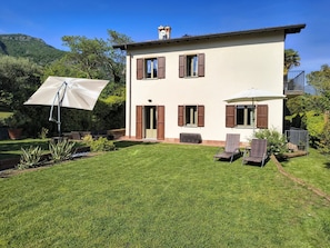 Une maison à deux étages avec un jardin, un espace extérieur aménagé pour s’asseoir et une vue dégagée sur le paysage environnant.