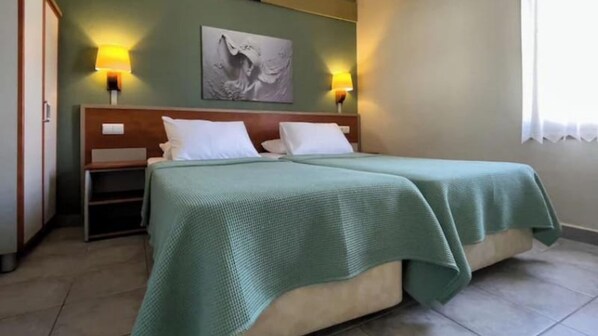 A hotel room with a bed, two bedside lamps, a nightstand, a wardrobe, and a painting on the wall. - Green Mar Hotel (Marmaris)