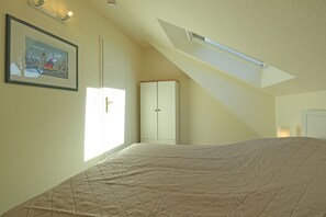 Ein Schlafzimmer mit Bett, Kleiderschrank, einer Tür und einem Oberlicht.