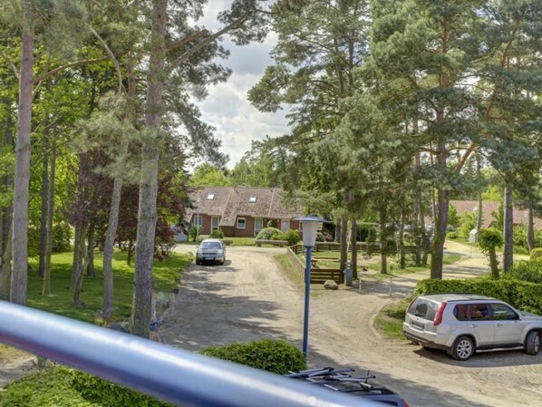 A residential area with a paved driveway, parked cars, and a house with a sloped roof.