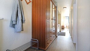 Een gang met een houten garderobe, een droogrek en een radiator.
