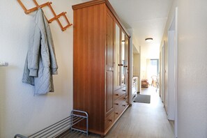A hallway with a wooden wardrobe, a drying rack, and a radiator.