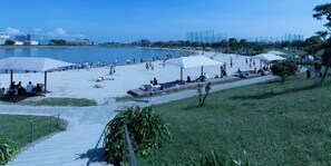 Une plage avec des parasols, des gens et un ciel dégagé.
