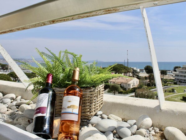 Dos botellas de vino en un balcón con vistas al mar y edificios.