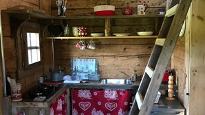 Una cocina pequeña con paredes de madera, estufa integrada, lavamanos y refrigerador.