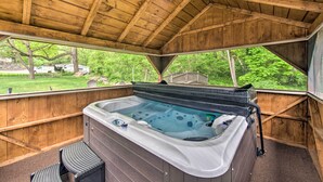 Ein Whirlpool in einem hölzernen Pavillon mit Blick auf eine Wiese und Bäume.
