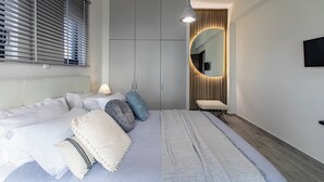 A modern bedroom with a large bed, bedside tables, a wardrobe, and a mirror with a unique light design. - 300mt to Restaurants & Supermarkets *1km to Beach*Gym (Plaka)