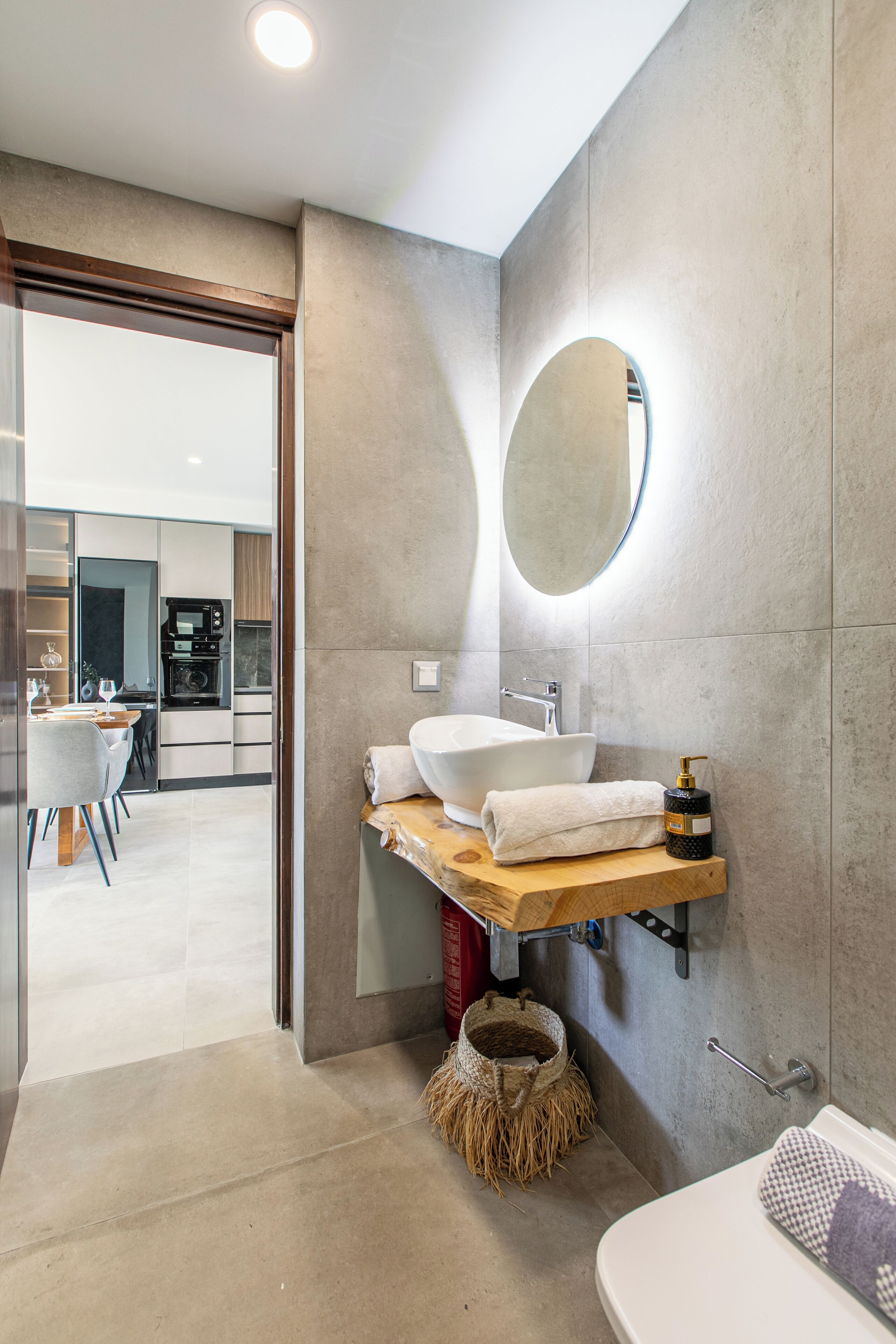 A modern bathroom with a large mirror, a white sink, and a wooden vanity.