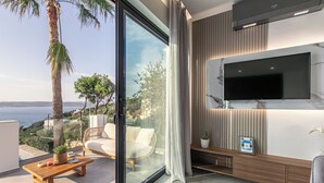 A modern living room with a large TV, comfortable seating, and a view of the sea. - 300mt to Restaurants & Supermarkets *1km to Beach*Gym (Plaka)