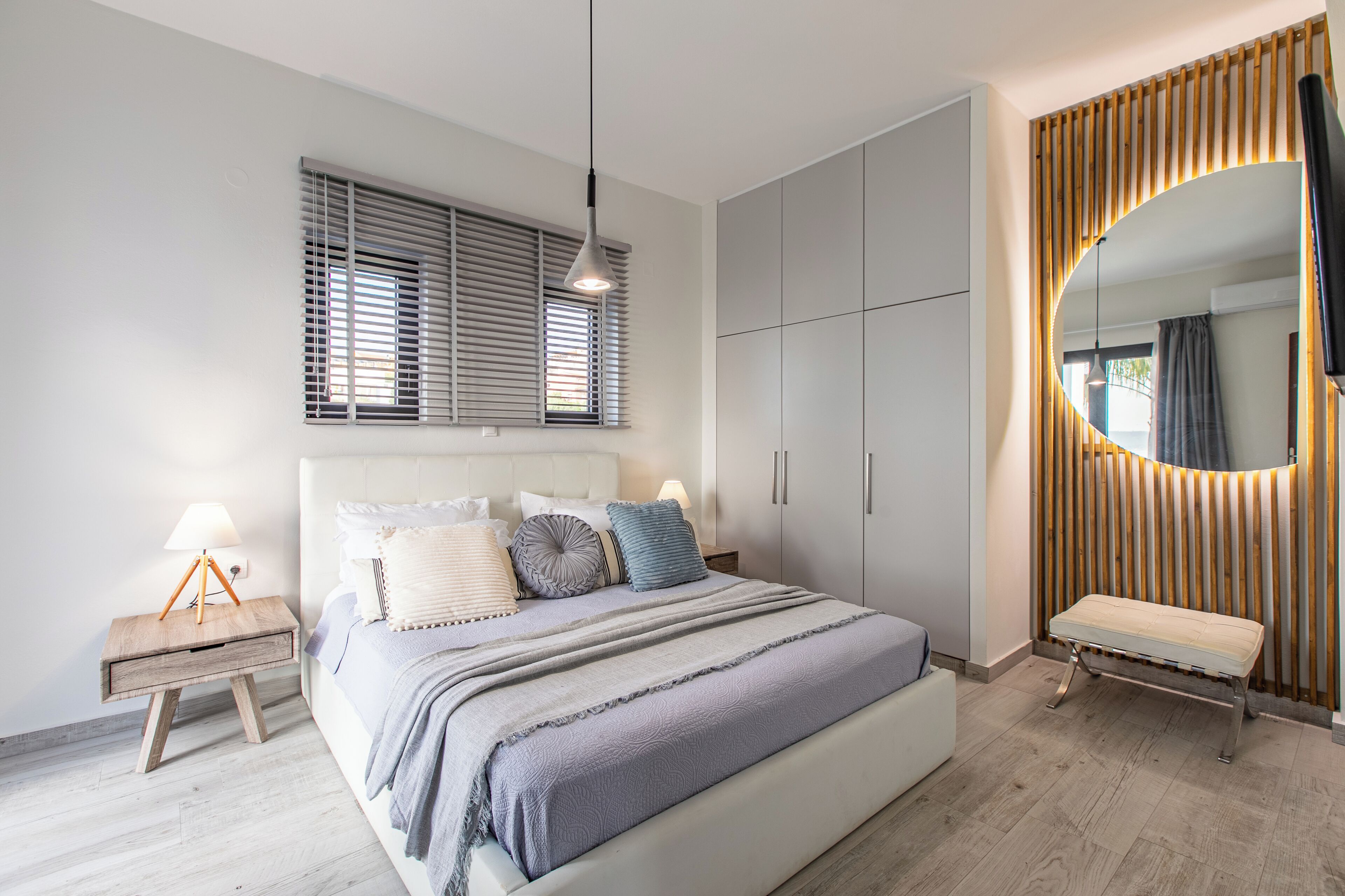 Une chambre moderne avec un grand lit, des tables de chevet, un miroir et des armoires intégrées.