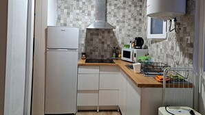 A compact kitchen with a refrigerator, microwave, kettle, and a small sink. - Casa Antique Barcelona&Barca (Hospitalet de Llobregat)