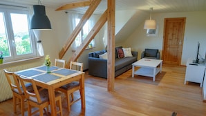 A cozy loft-style living space with a dining area, a sofa, and a TV. - Ferienwohnung Liebenau - Ferienwohnung Wölfel (Gößweinstein)