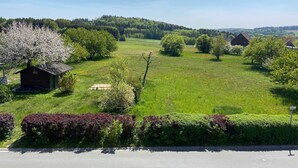 A rural landscape with a small wooden cabin, a field, and a road. - Ferienwohnung Liebenau - Ferienwohnung Wölfel (Gößweinstein)