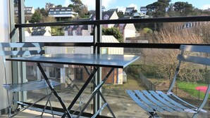A balcony with a table and chairs, overlooking a residential area with houses and trees. - New apartment 2/4 people, 100m to beach, Perros-Guirec (Perros-Guirec)