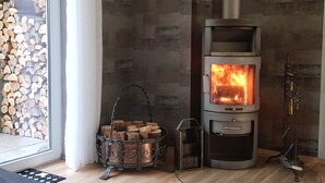 Ein Kaminofen mit Holzscheiten, einem Metallkorb und einem Schornstein.