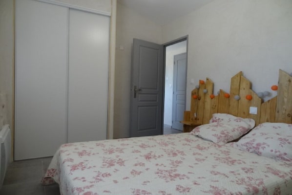 A bedroom with a bed, a wooden headboard, and a door.