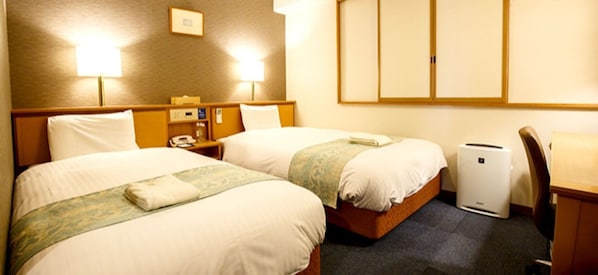 Two single beds with pillows and blankets, a nightstand with a lamp and phone, and a heater for comfort.