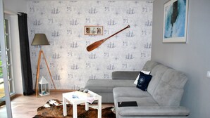A living room with a grey sofa, a white coffee table, a brown and white rug, a lamp, and a framed picture on the wall. - Apartment "SeeLiebe" in Bad Saarow (Bad Saarow)