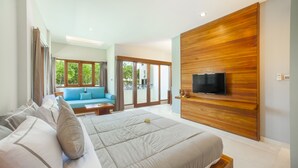 Un dormitorio moderno con una cama grande, un televisor montado en una pared de madera, y vistas al exterior a través de amplias ventanas.