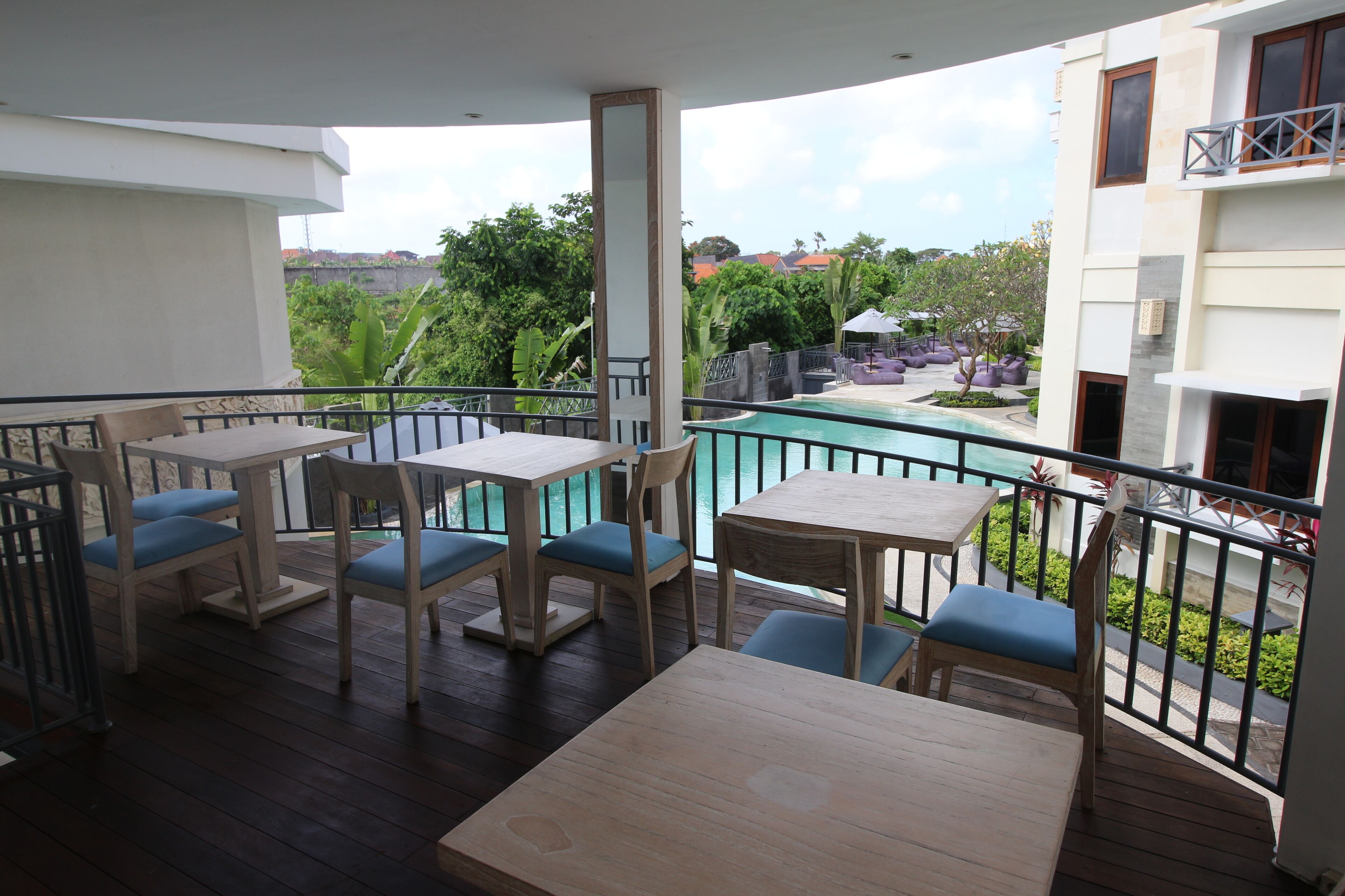A balcony with wooden furniture and a view of a swimming pool.