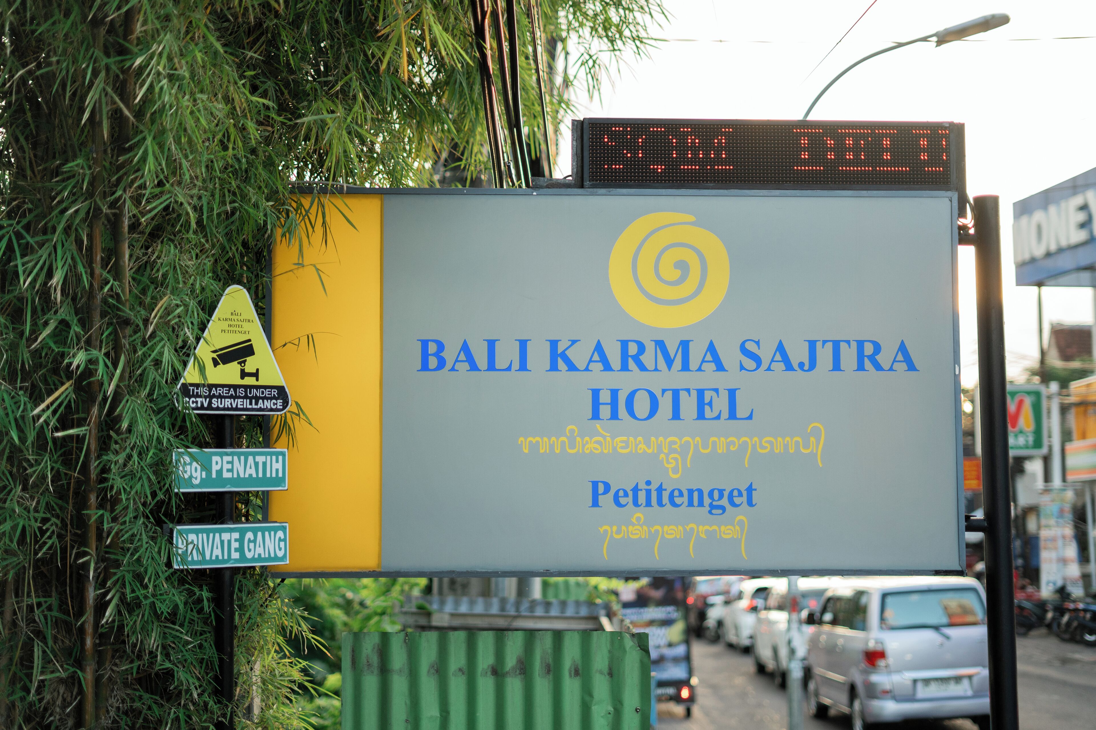 A sign for Bali Karma Sajtra Hotel with a digital display above it.