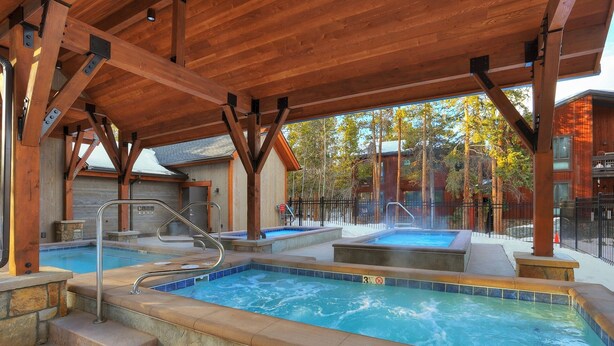 Ett avskärmat utomhuspoolområde med en bubbelpool, stentrappor och ett trädäck.