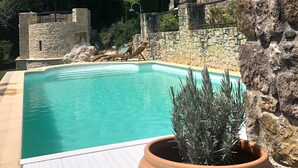 A stone building with a tower, a swimming pool, and a potted plant. - Luxury apartment in a renovated Chateau with a  view of the Pyrenees. (Mouzens)
