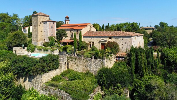 A historic stone building with a tower, surrounded by lush greenery and a stone wall. - Luxury apartment in a renovated Chateau with a  view of the Pyrenees. (Mouzens)