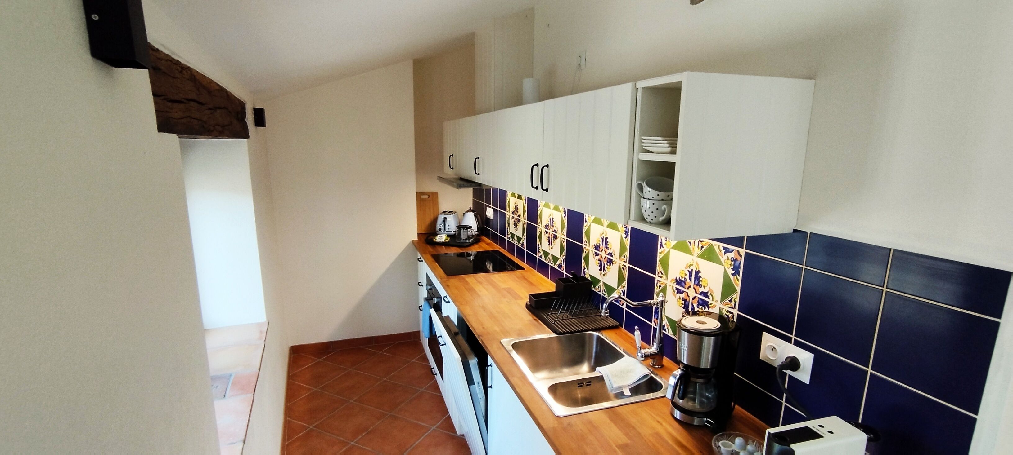 A narrow kitchen with a wooden countertop, a sink, and a coffee maker.