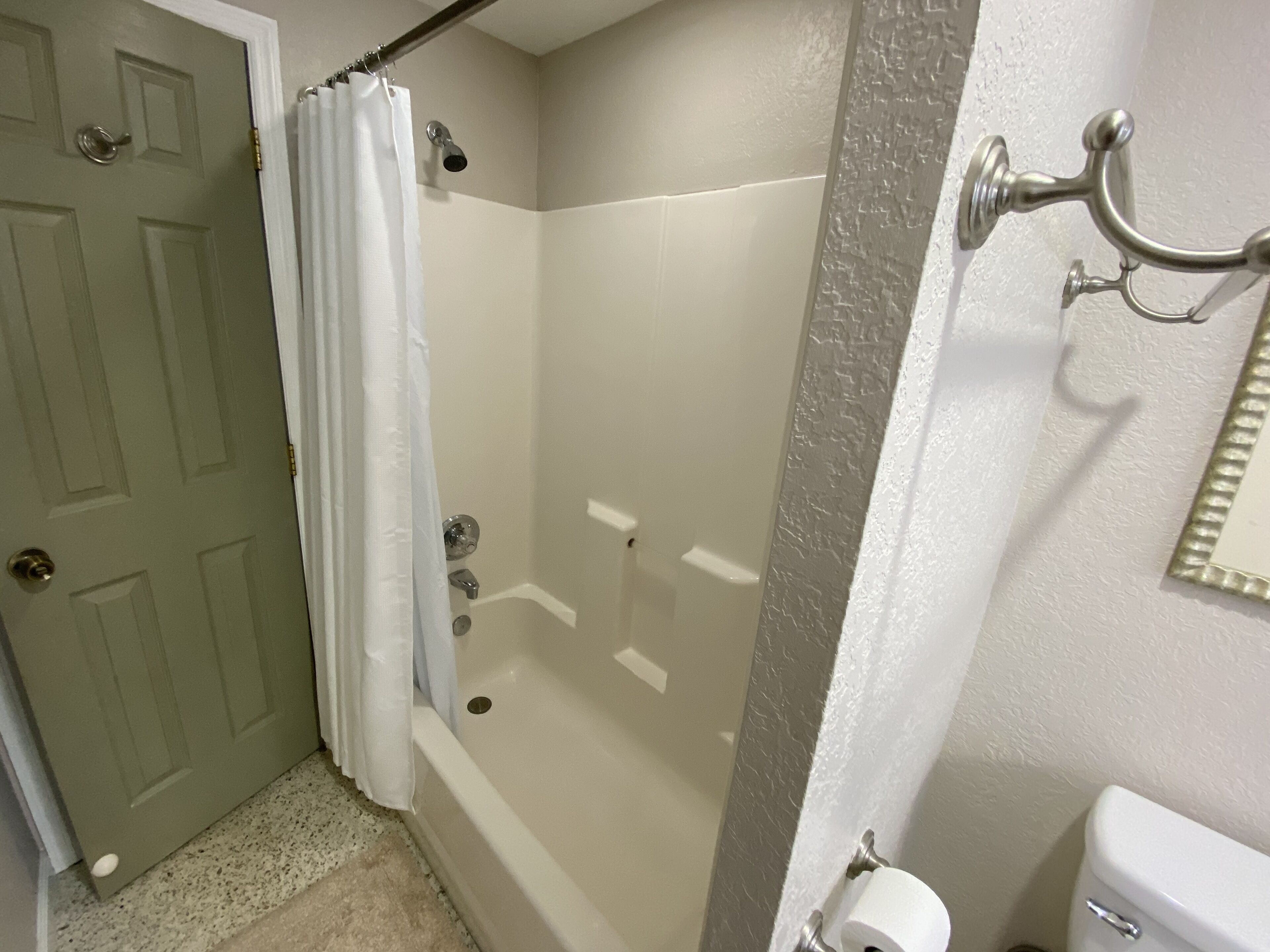Un baño con bañera, inodoro y cortina de ducha.