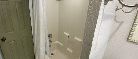Un baño con bañera, inodoro y cortina de ducha.