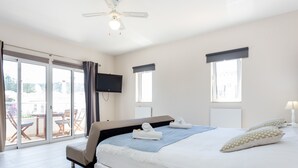 A hotel room with a bed, a TV, a ceiling fan, and a balcony with outdoor furniture. - Mariners (5) - Bright and stylish apartment - 2-minute walk to the beach (Luz)